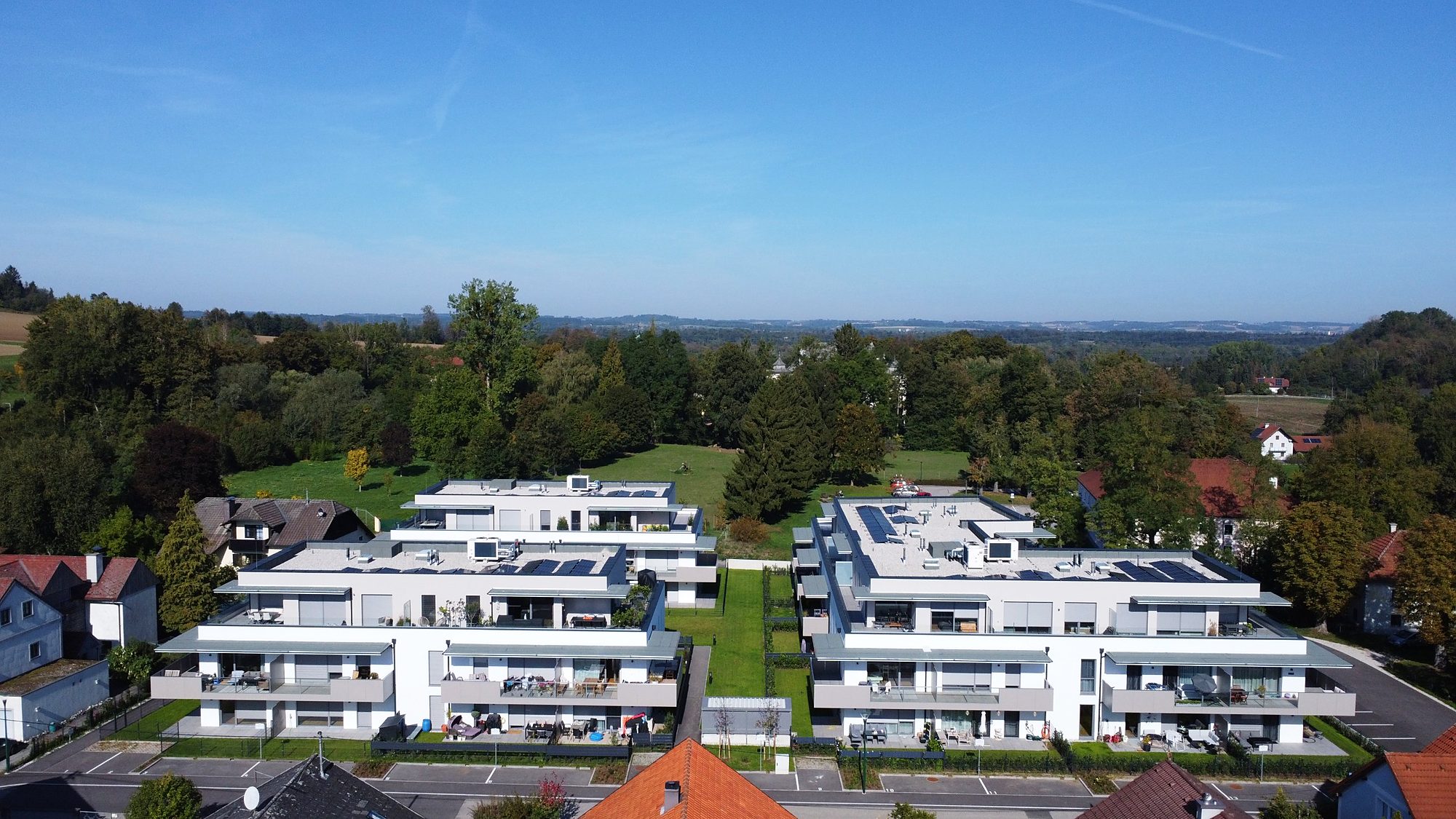 Luftaufnahme der drei Häuser von Landliebe Living mit Bäumen und Wiesen dahinter